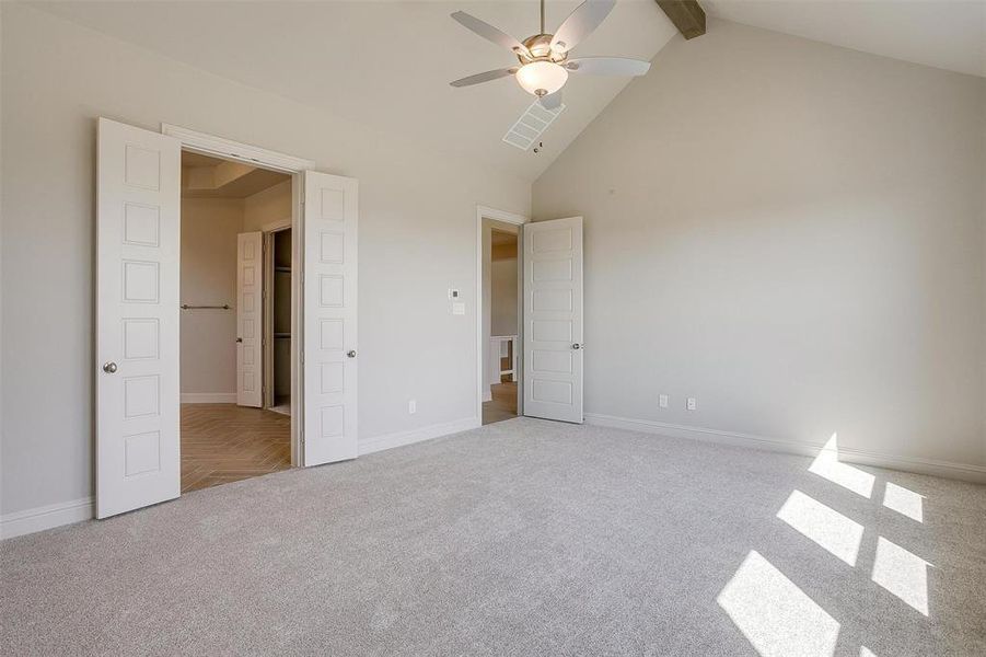 Unfurnished bedroom with ceiling fan, beam ceiling, high vaulted ceiling, and carpet floors