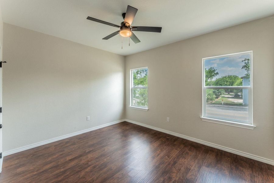 Spacious room featuring wood-finish flooring, light neutral wall paint, and white trim