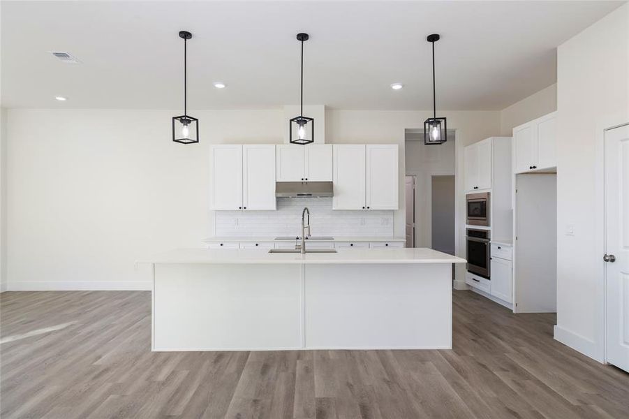 Kitchen featuring sink, a center island with sink, white cabinets, and appliances with stainless steel finishes