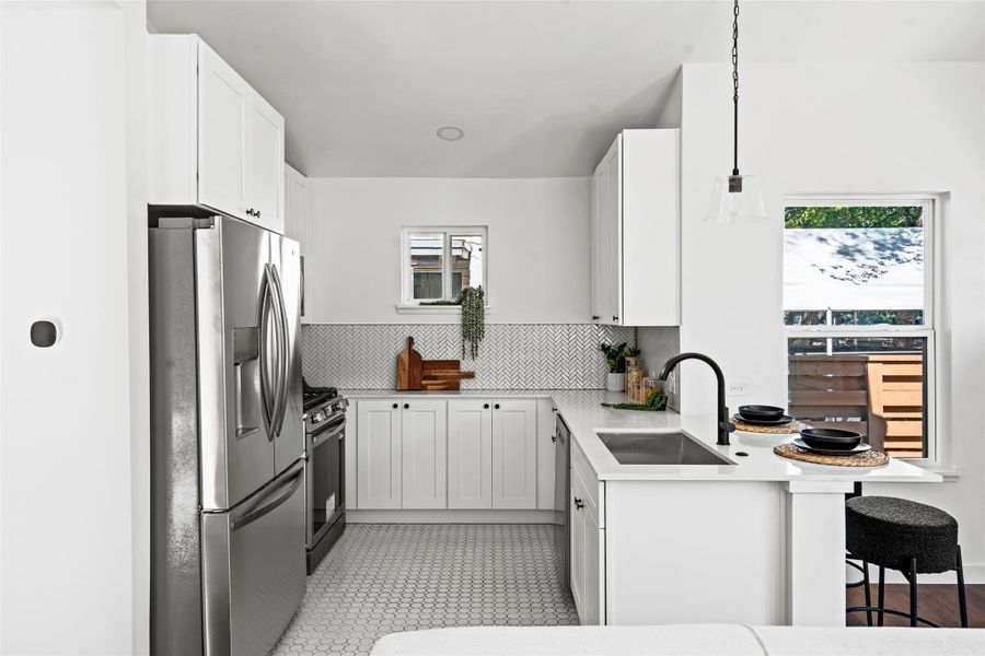 Kitchen with appliances with stainless steel finishes, white cabinets, decorative backsplash, and decorative light fixtures