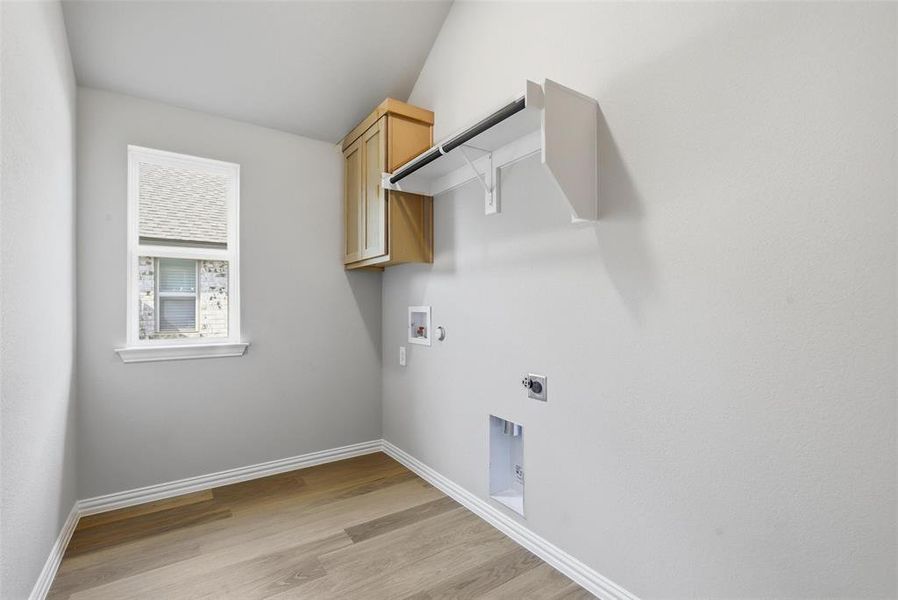 Washroom with cabinet space, light wood-type flooring, hookup for a washing machine, hookup for an electric dryer, and gas dryer hookup Washroom with cabinet space, light wood-type flooring, hookup for a washing machine, hookup for an electric dryer, and gas dryer hookup
