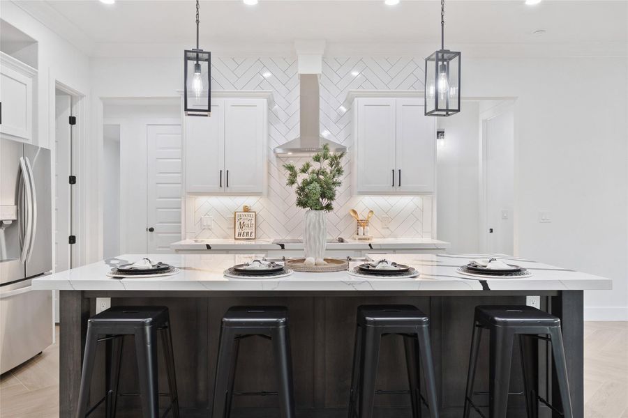 Kitchen featuring a kitchen bar, crown molding, white cabinets, pendant lighting, and stainless steel fridge
