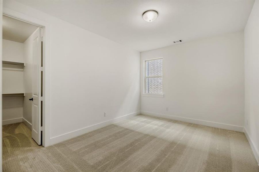 Unfurnished bedroom featuring light carpet and a spacious closet