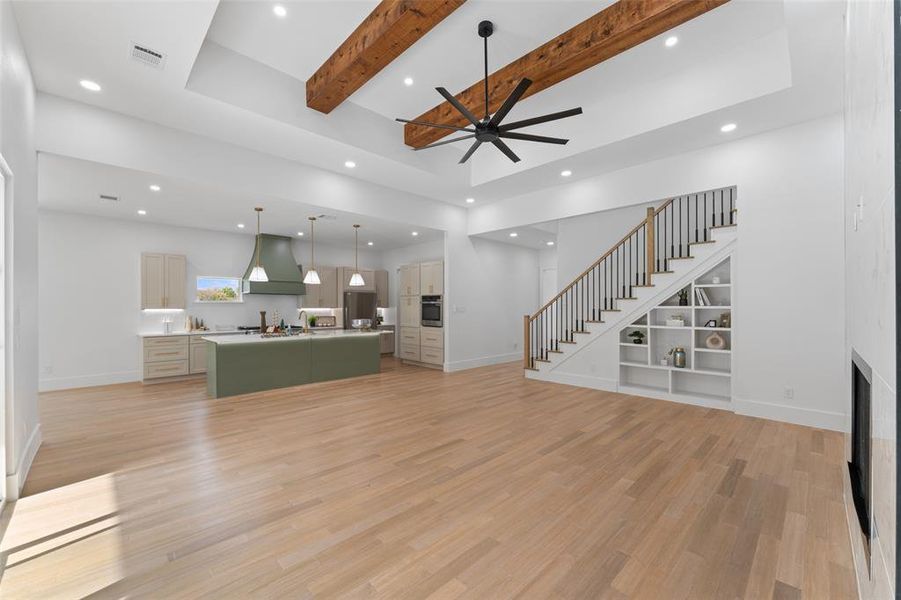 Living room featuring stairway, recessed lighting, light wood-type flooring, beamed ceiling, and ceiling fan