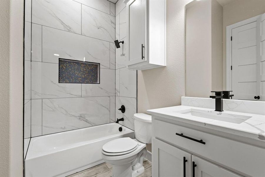 Full bathroom with shower / bath combination, vanity, and a textured wall