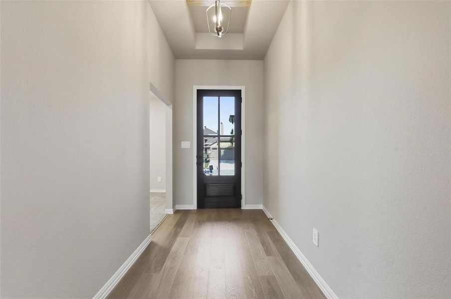Doorway to outside with wood finished floors and a tray ceiling Doorway to outside with wood finished floors and a tray ceiling