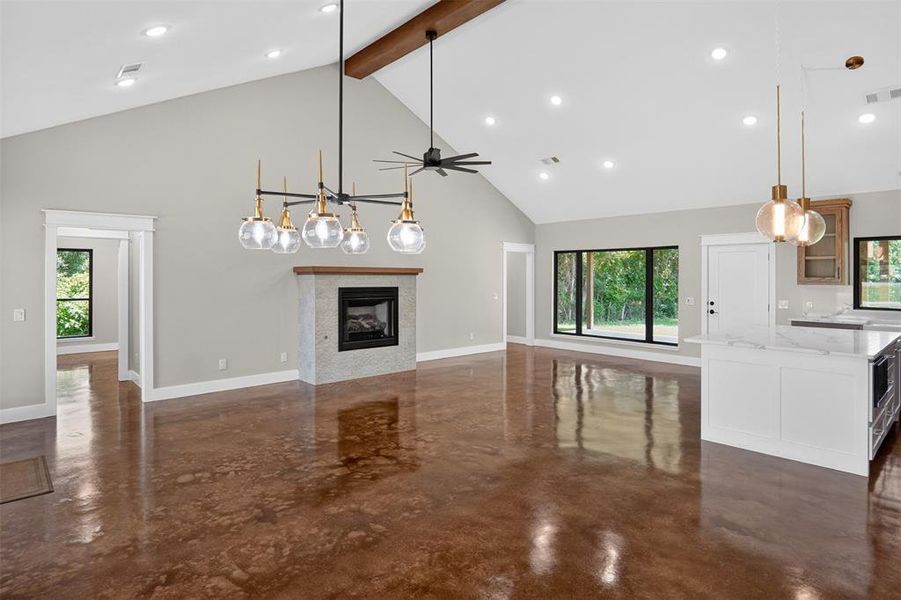 Expansive living area featuring vaulted ceilings with an exposed wood beam, recessed lighting, and polished concrete flooring Expansive living area featuring vaulted ceilings with an exposed wood beam, recessed lighting, and polished concrete flooring