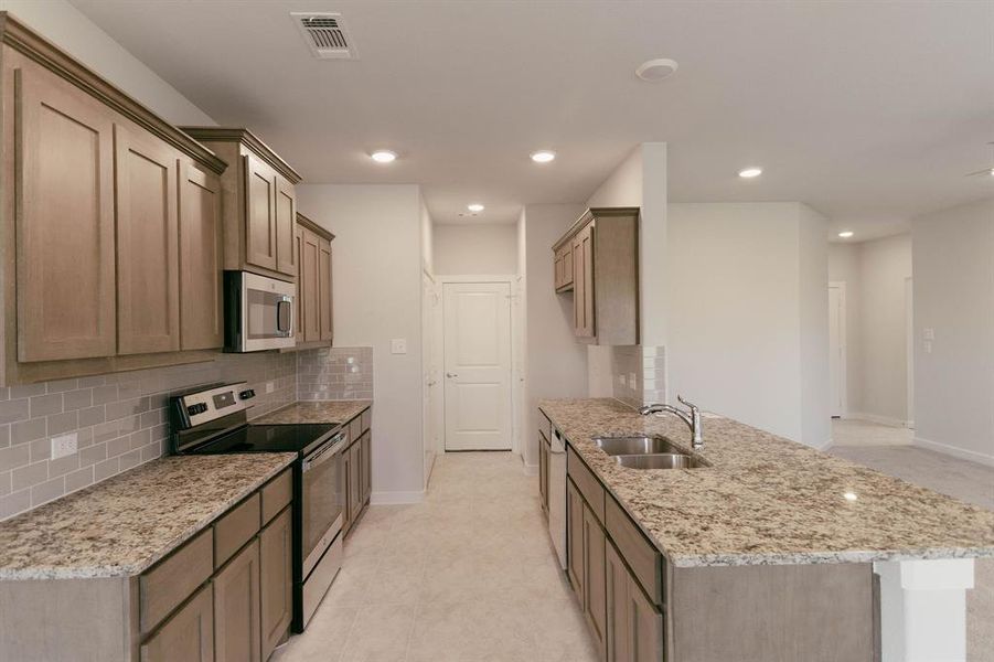 Kitchen featuring light tile patterned flooring, sink, light stone countertops, appliances with stainless steel finishes, and backsplash