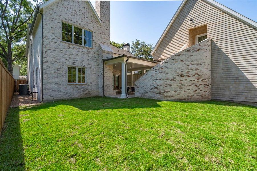 Rear view of house with central air condition unit, a patio area, and a yard