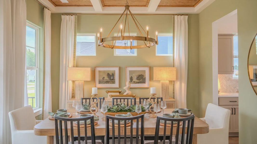 Dining area with coffered ceiling, access to kitchen, and bright natural lighting from windows Dining area with coffered ceiling, access to kitchen, and bright natural lighting from windows