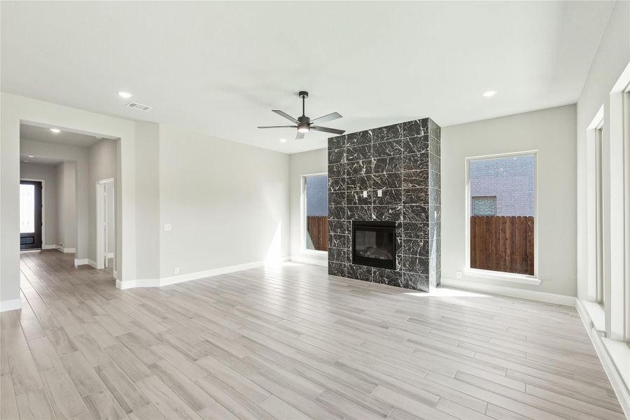 Open living room with light wood floors, ceiling fan, and dark marble tile fireplace surround Open living room with light wood floors, ceiling fan, and dark marble tile fireplace surround
