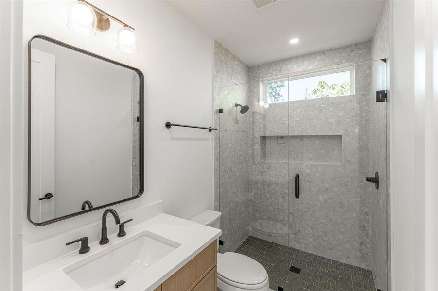 Bathroom with vanity, an enclosed shower, and toilet