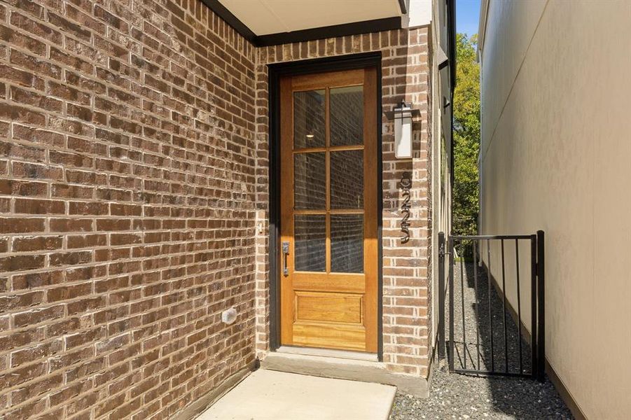 Doorway to property with brick siding and a gate