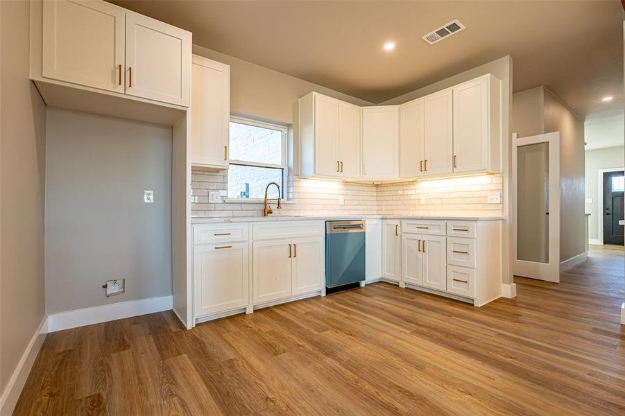 Kitchen with white cabinetry, light wood-style floors, and decorative backsplash Kitchen with white cabinetry, light wood-style floors, and decorative backsplash