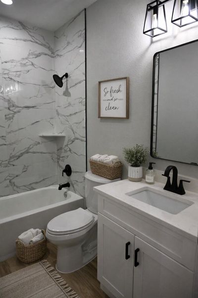 Full bath featuring vanity, a combined bath / shower with marble appearance, and wood finished floors