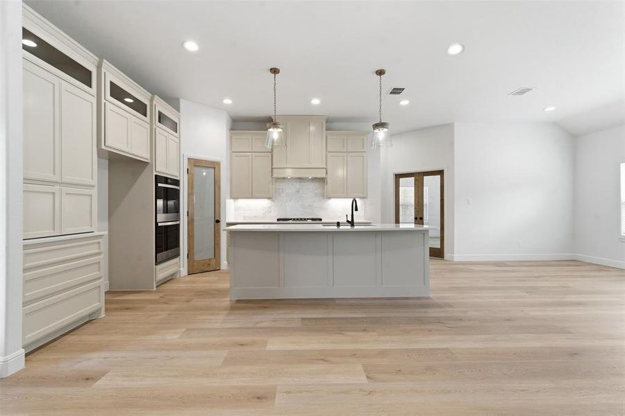 Kitchen with pendant lighting, tasteful backsplash, recessed lighting, light wood-type flooring, and an island with sink Kitchen with pendant lighting, tasteful backsplash, recessed lighting, light wood-type flooring, and an island with sink