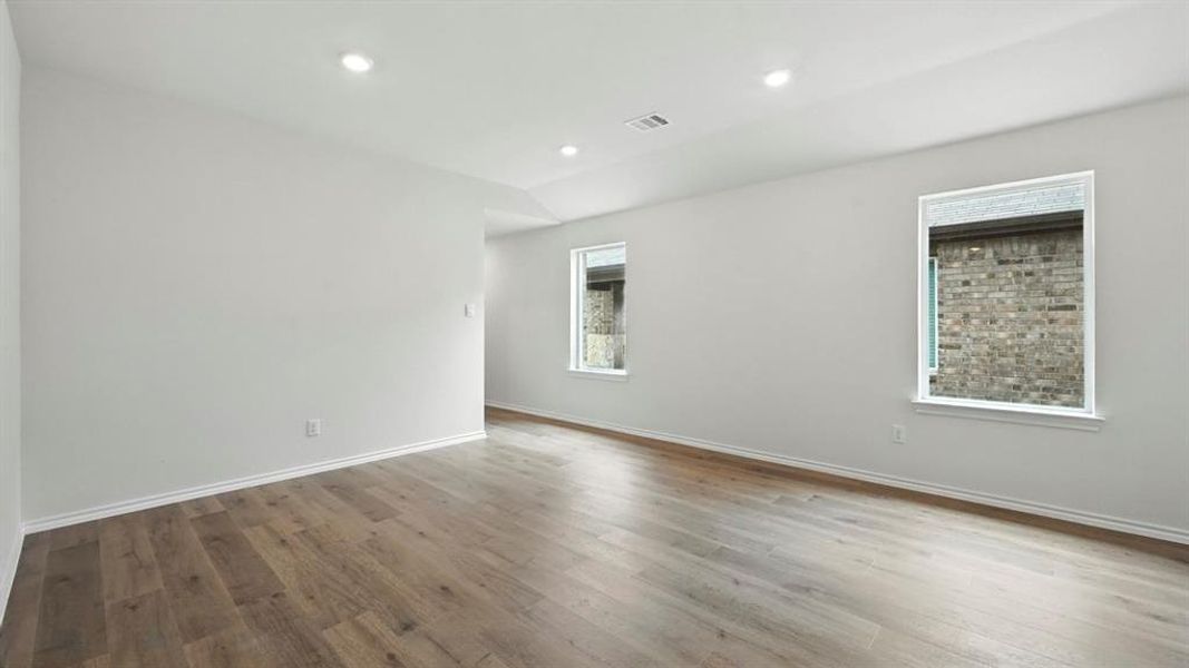 Spacious interior featuring wood-finish flooring, recessed lighting, and white walls Spacious interior featuring wood-finish flooring, recessed lighting, and white walls