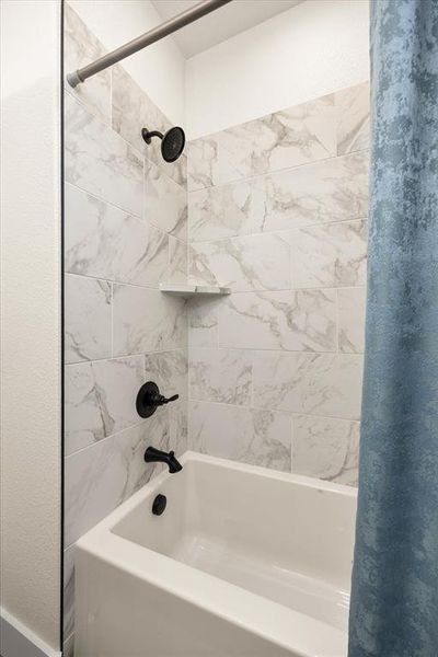 Bathtub with white subway tile surround featuring a subtle grey veining pattern