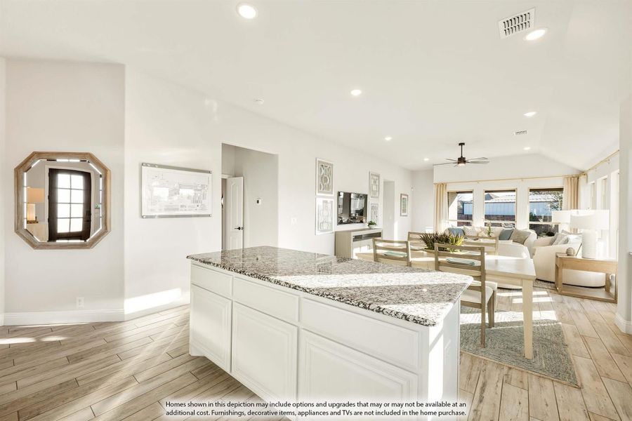 Open-concept kitchen with white island and granite countertop, flowing into dining and living areas with light wood floors Open-concept kitchen with white island and granite countertop, flowing into dining and living areas with light wood floors