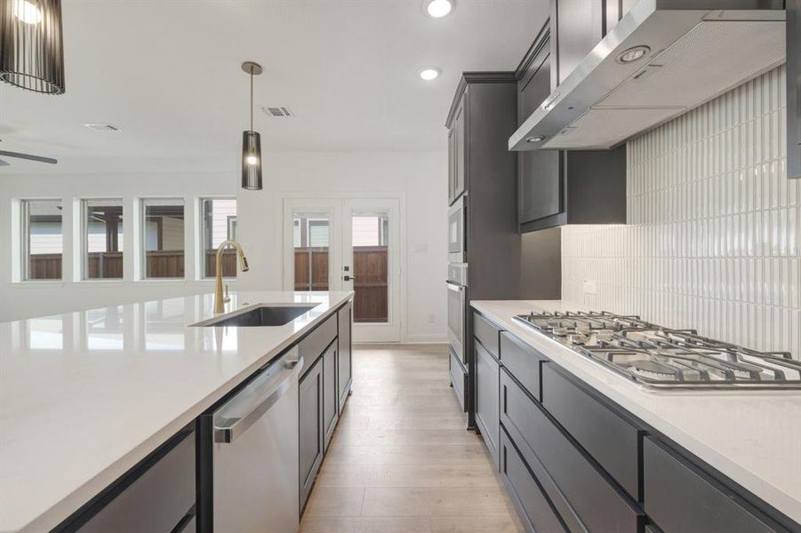 Modern kitchen featuring light countertops, dark cabinetry, and wood-finish flooring