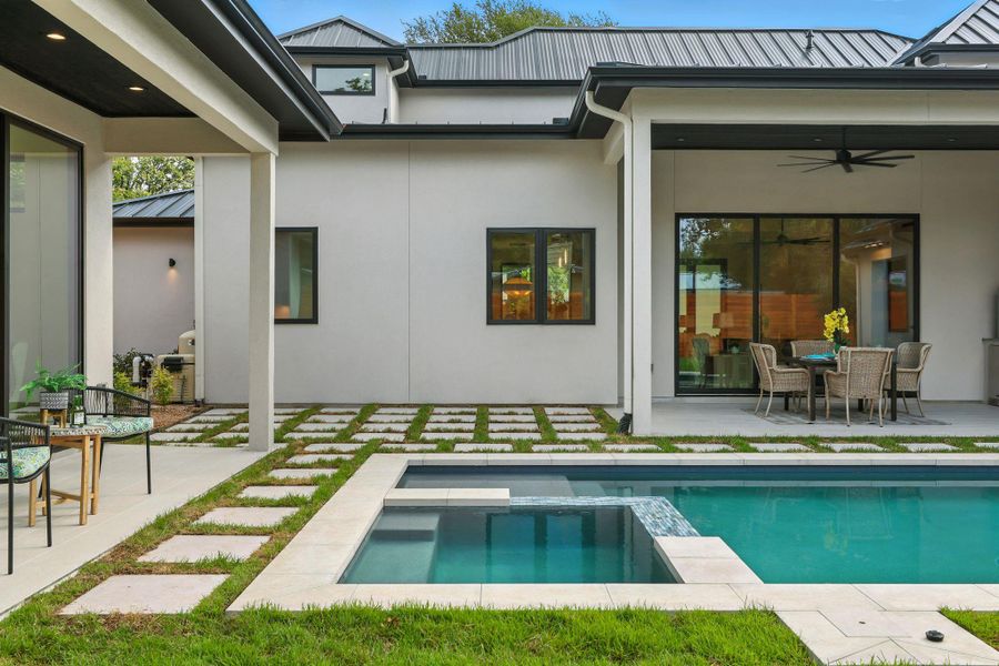 Back of house with a patio area, a metal roof, a pool with connected hot tub, a standing seam roof, and a ceiling fan Back of house with a patio area, a metal roof, a pool with connected hot tub, a standing seam roof, and a ceiling fan