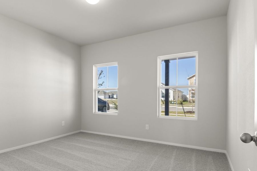 Image of a bedroom with light grey walls, tan carpeting, two windows and white trim