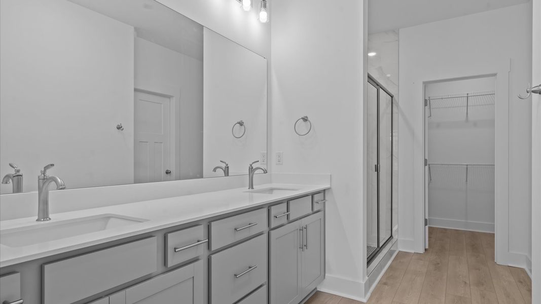 Spacious and modern primary bathroom with tiled walk-in shower and first-class double vanity setup