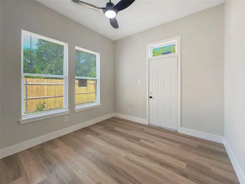Empty room featuring light wood-type flooring, baseboards, and ceiling fan outdoor access, with on suite bathroom. Empty room featuring light wood-type flooring, baseboards, and ceiling fan outdoor access, with on suite bathroom.