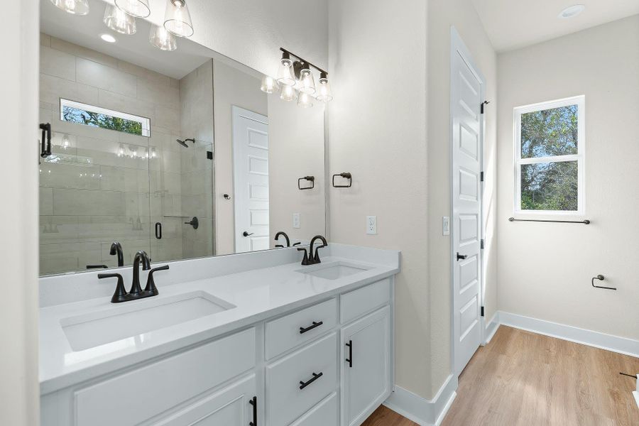 Full bathroom featuring light wood-style floors, double vanity, a stall shower, and recessed lighting