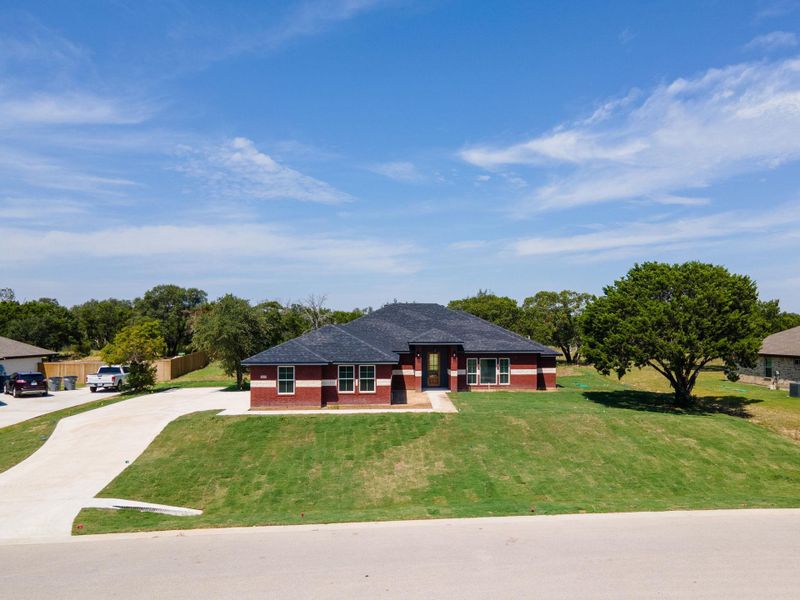 Prairie-style house featuring brick siding, driveway, a front yard, and a shingled roof