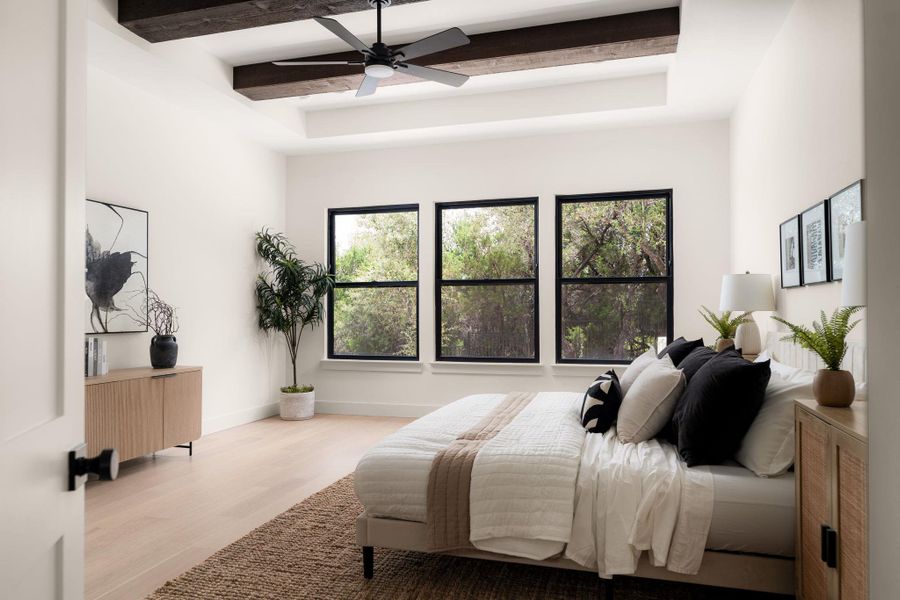 A tranquil primary bedroom features exposed wooden beams and an abundance of natural light filtering through expansive windows.