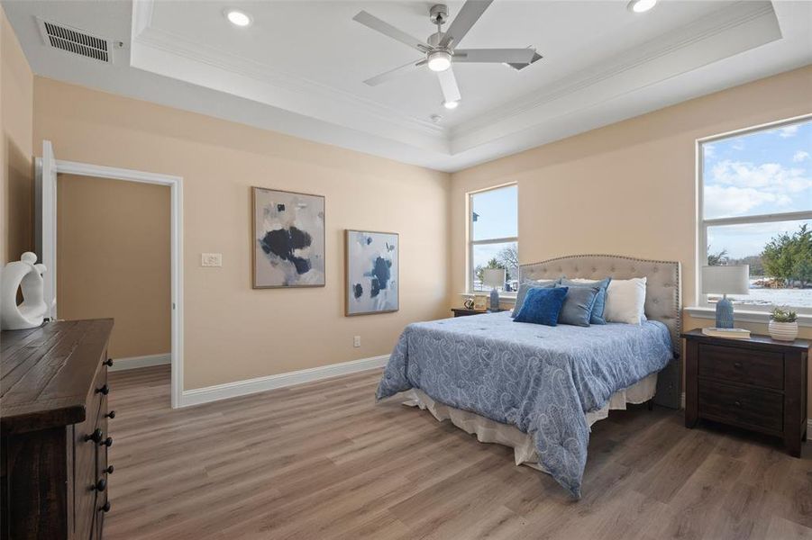 Bedroom featuring light wood-finish flooring, a tray ceiling, and recessed lighting Bedroom featuring light wood-finish flooring, a tray ceiling, and recessed lighting