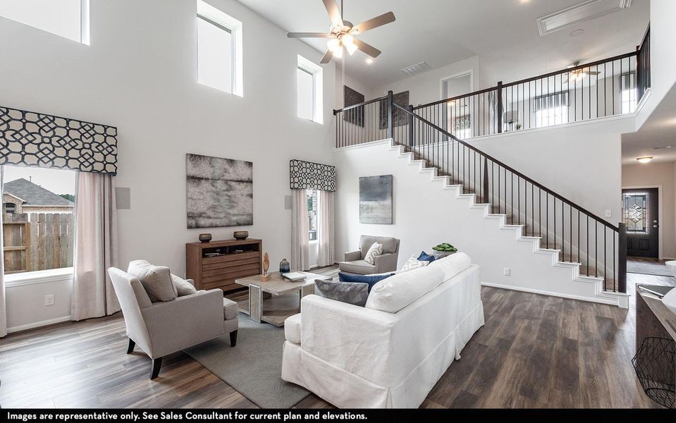 Living area featuring a ceiling fan, dark wood-style floors, and a high ceiling