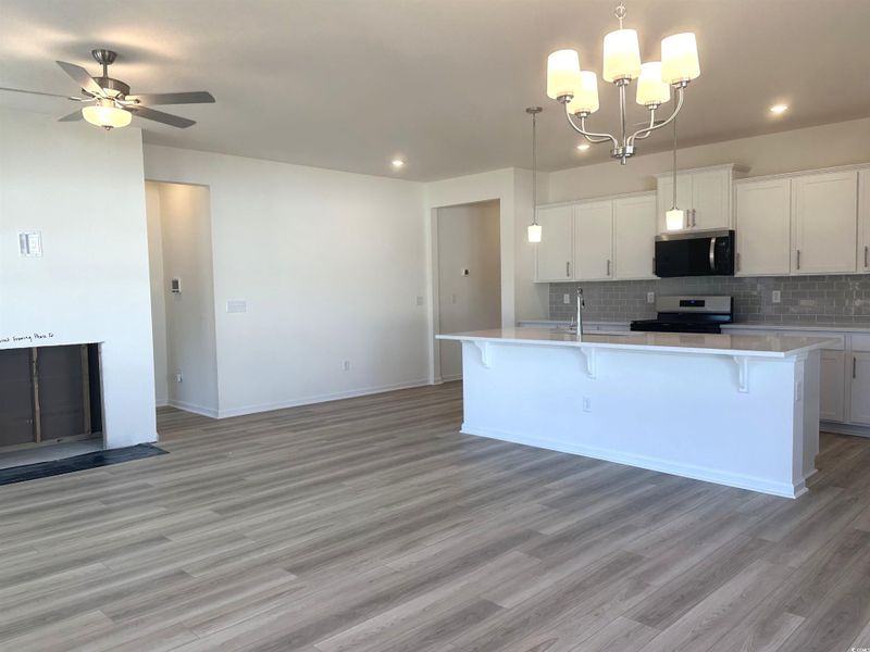 Kitchen with white cabinets, a breakfast bar, appliances with stainless steel finishes, and backsplash