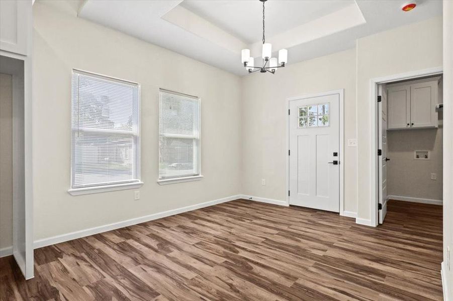 Foyer entrance featuring a raised ceiling, dark wood-style flooring, and a chandelier Foyer entrance featuring a raised ceiling, dark wood-style flooring, and a chandelier