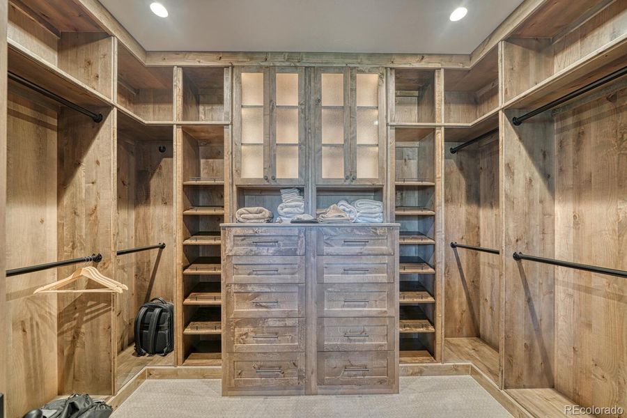 The walk-in closet is fully outfitted with glass-front cabinets and solid wood shelving. The walk-in closet is fully outfitted with glass-front cabinets and solid wood shelving.