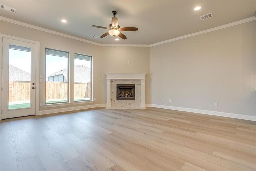 Unfurnished living room with ceiling fan, light hardwood / wood-style flooring, ornamental molding, and a fireplace