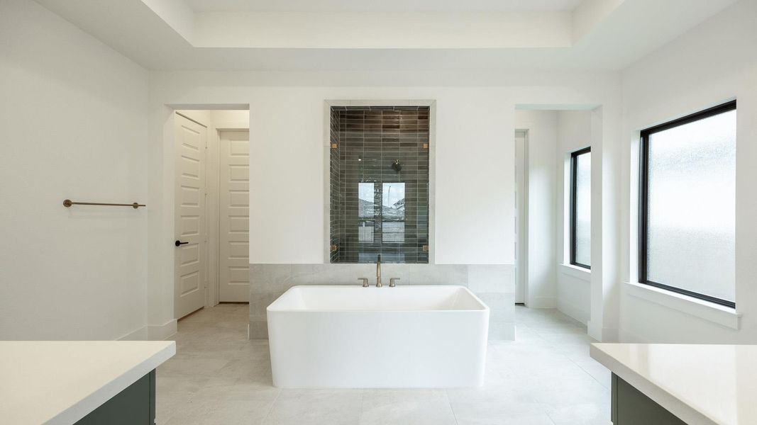 Bathroom featuring a freestanding bath, vanity, tile patterned flooring, and tile walls Bathroom featuring a freestanding bath, vanity, tile patterned flooring, and tile walls