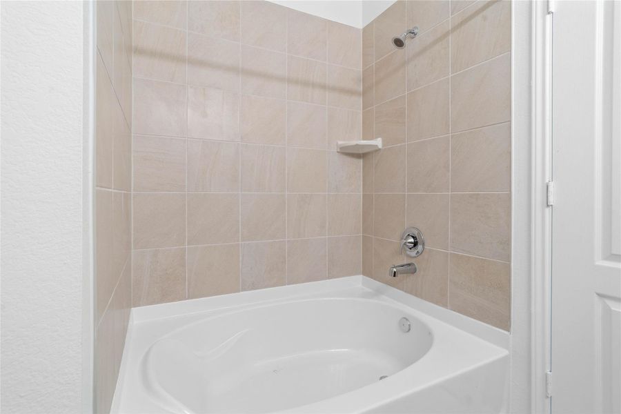 This additional view of the primary bath showcases an oversized tub/shower combination with tile surround. This additional view of the primary bath showcases an oversized tub/shower combination with tile surround.