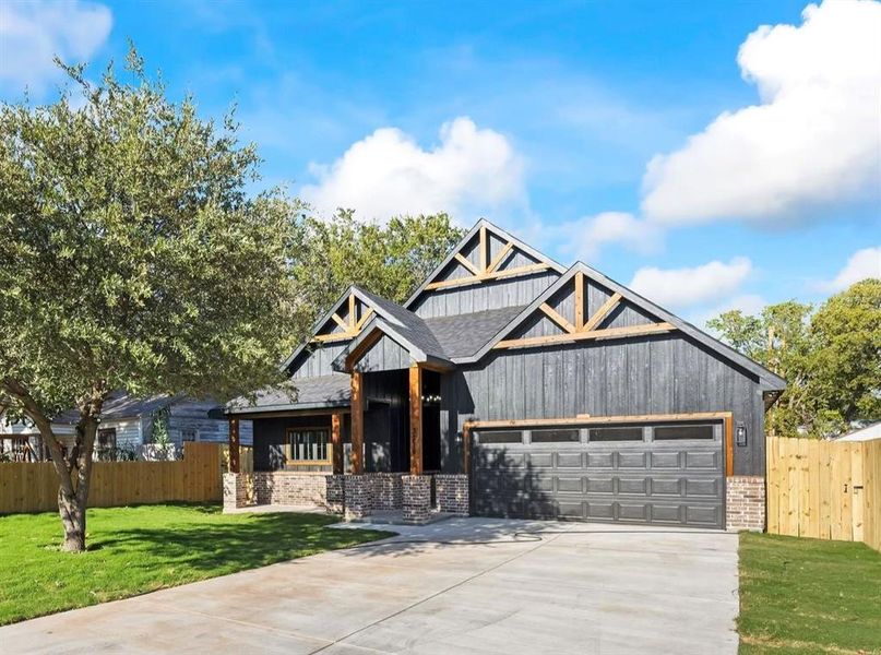 Modern farmhouse with brick siding, concrete driveway, and an attached garage Modern farmhouse with brick siding, concrete driveway, and an attached garage
