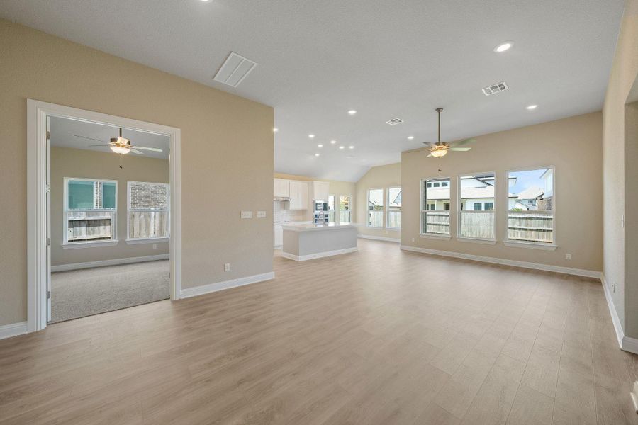 Unfurnished living room featuring ceiling fan, recessed lighting, vaulted ceiling, and light wood-style flooring