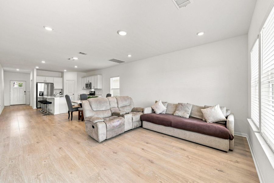 Smooth wood floors flow seamlessly through this open-concept living space into the modern kitchen.