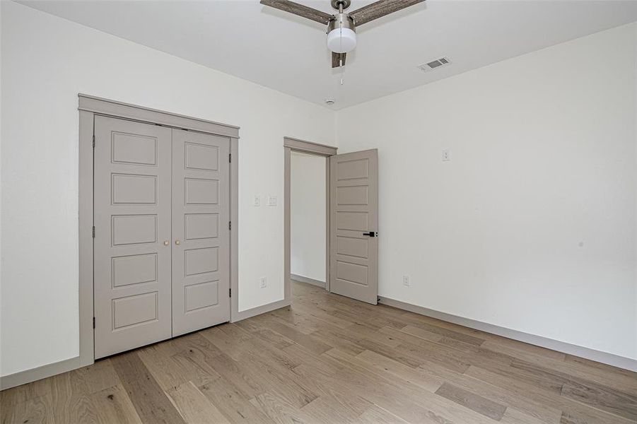 bedroom featuring light wood-type flooring, a ceiling fan, and a closet