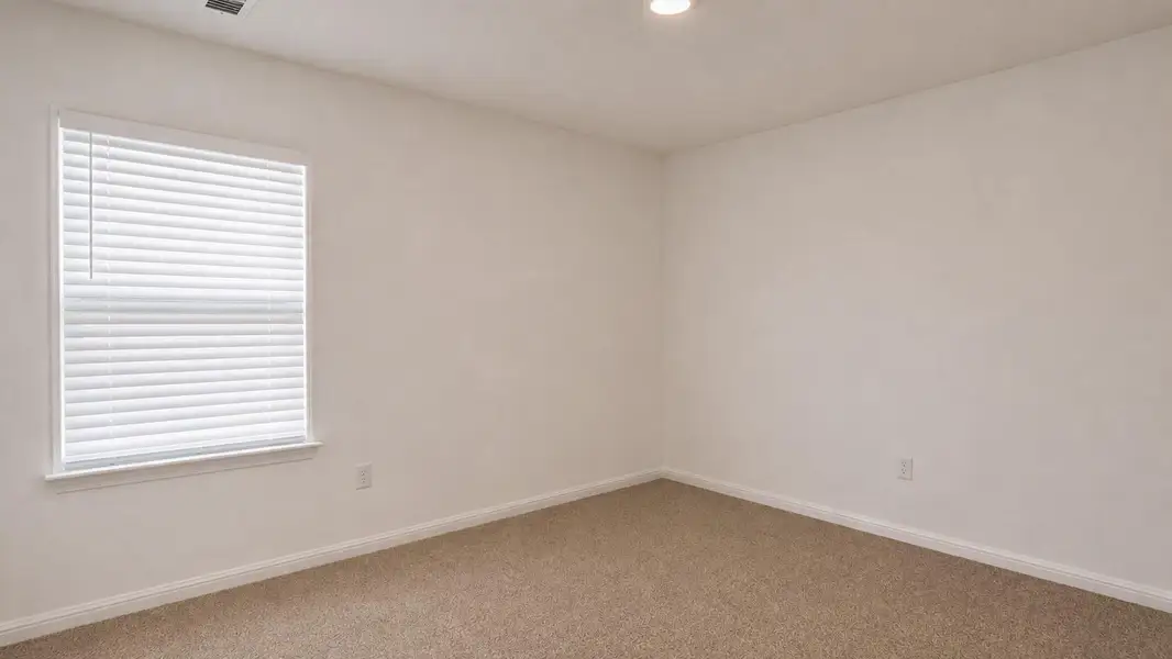 A well-lit bedroom features plush carpeting and ready for personalization. A well-lit bedroom features plush carpeting and ready for personalization.