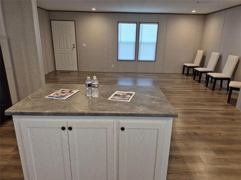 Kitchen with dark wood-style flooring, a center island, white cabinetry, and dark stone countertops