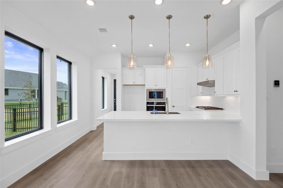 The stunning and generously sized breakfast bar is perfect for casual dining and entertaining. The elegant pendant lights provides additional lighting and refined style.