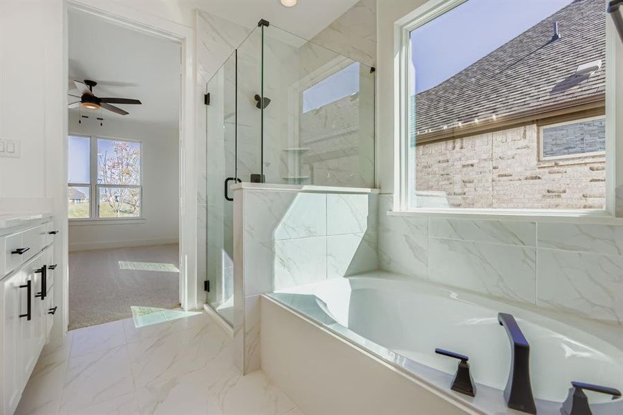 Bathroom with light marble finish flooring, a marble finish shower, vanity, a garden tub, and a ceiling fan Bathroom with light marble finish flooring, a marble finish shower, vanity, a garden tub, and a ceiling fan