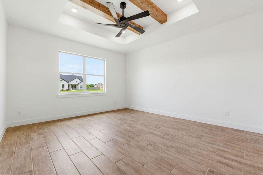 A tray ceiling with exposed wooden beams and a modern fan elevates this versatile interior space. A tray ceiling with exposed wooden beams and a modern fan elevates this versatile interior space.