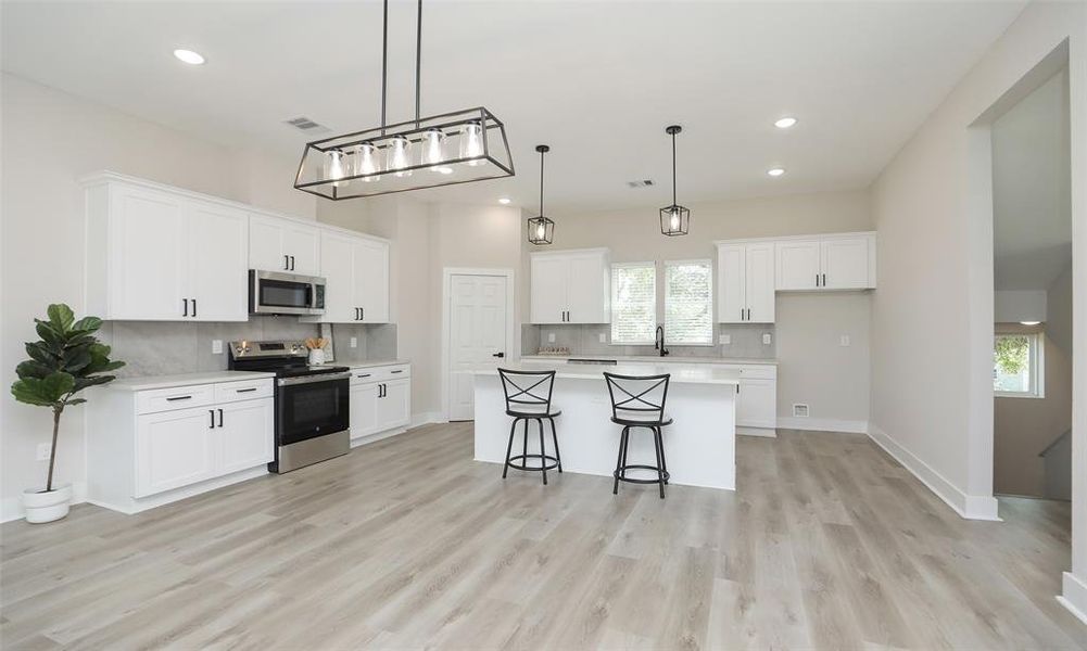 Modern farmhouse dining room light with complimentary pendant lights over the grand island, all with Edison bulbs.