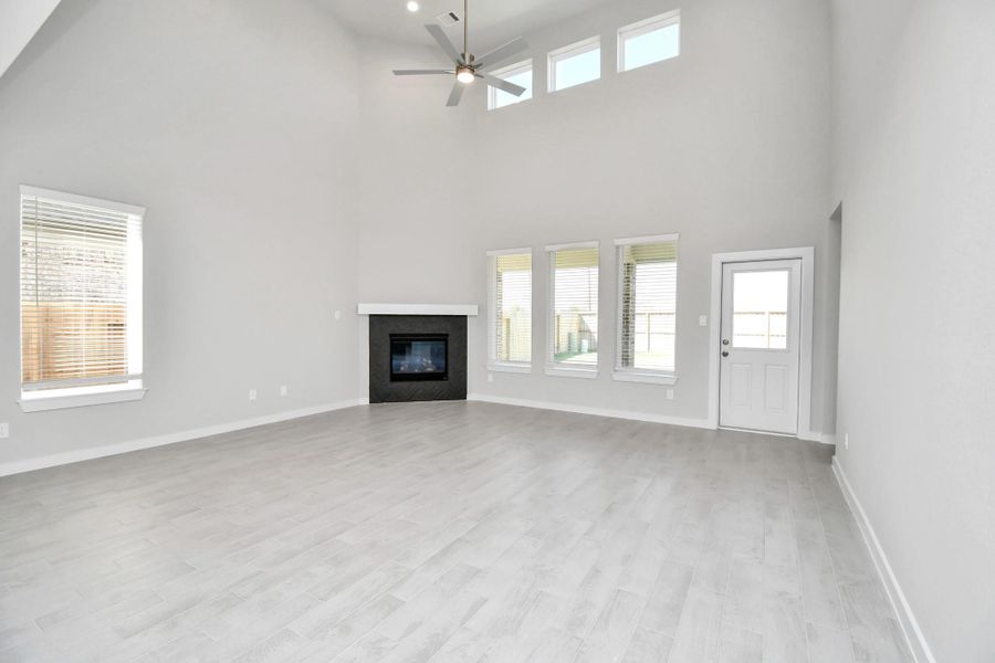 Welcome family and guests to your charming living room! With its high ceilings, recessed lighting, ceiling fan, custom paint, beautiful flooring, and large windows that let in abundant natural light, this room is perfect for gatherings. Sample photo of completed home with similar floor plan. Actual colors and selections may vary.